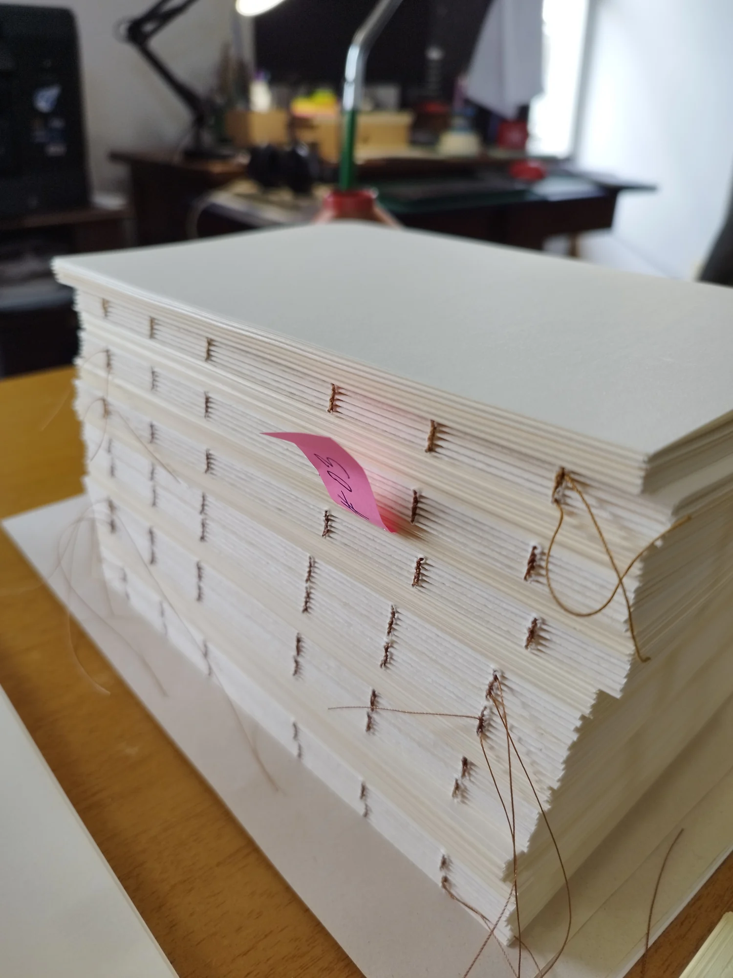 Pequeña pila de libros artesanales y herramientas de encuadernación sobre una mesa de trabajo