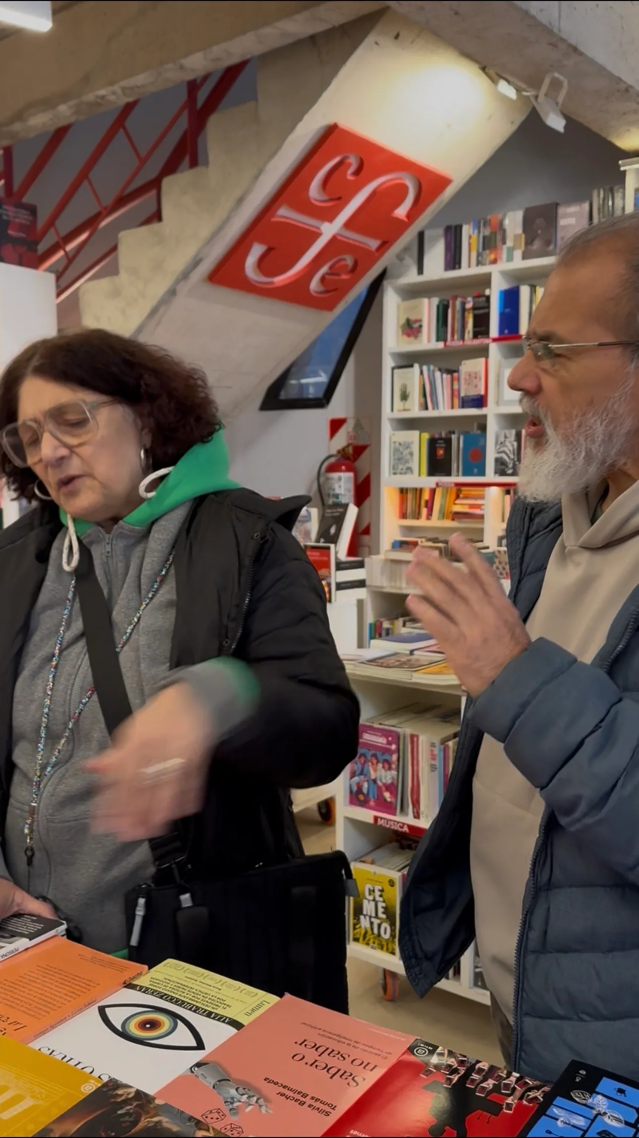 Alejandra Giménez y Fernando Rivero conversando junto a una mesa de libros